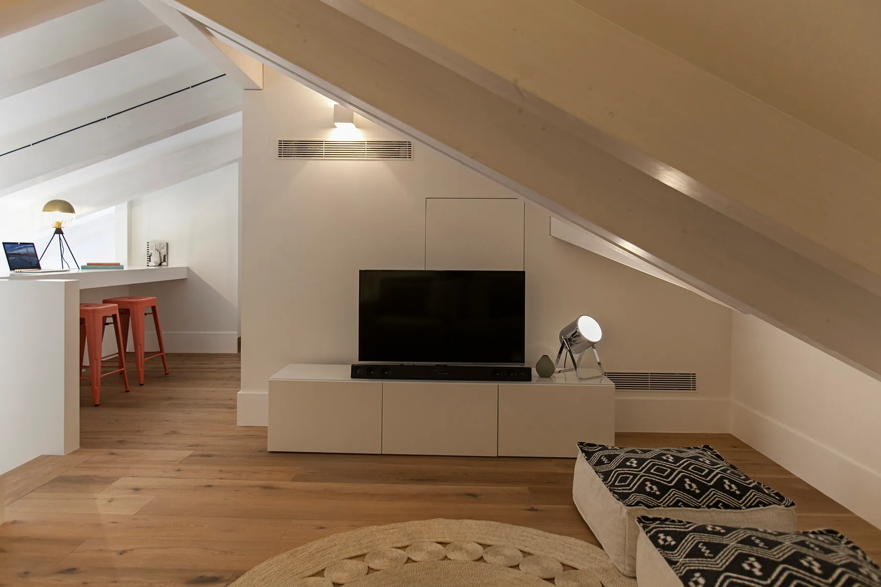 A sloped-ceiling living area with a television and a small dining counter.