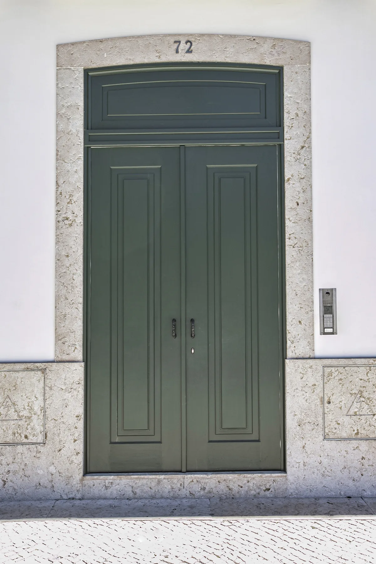 A dark green paneled entrance door set in a pale stone surround.