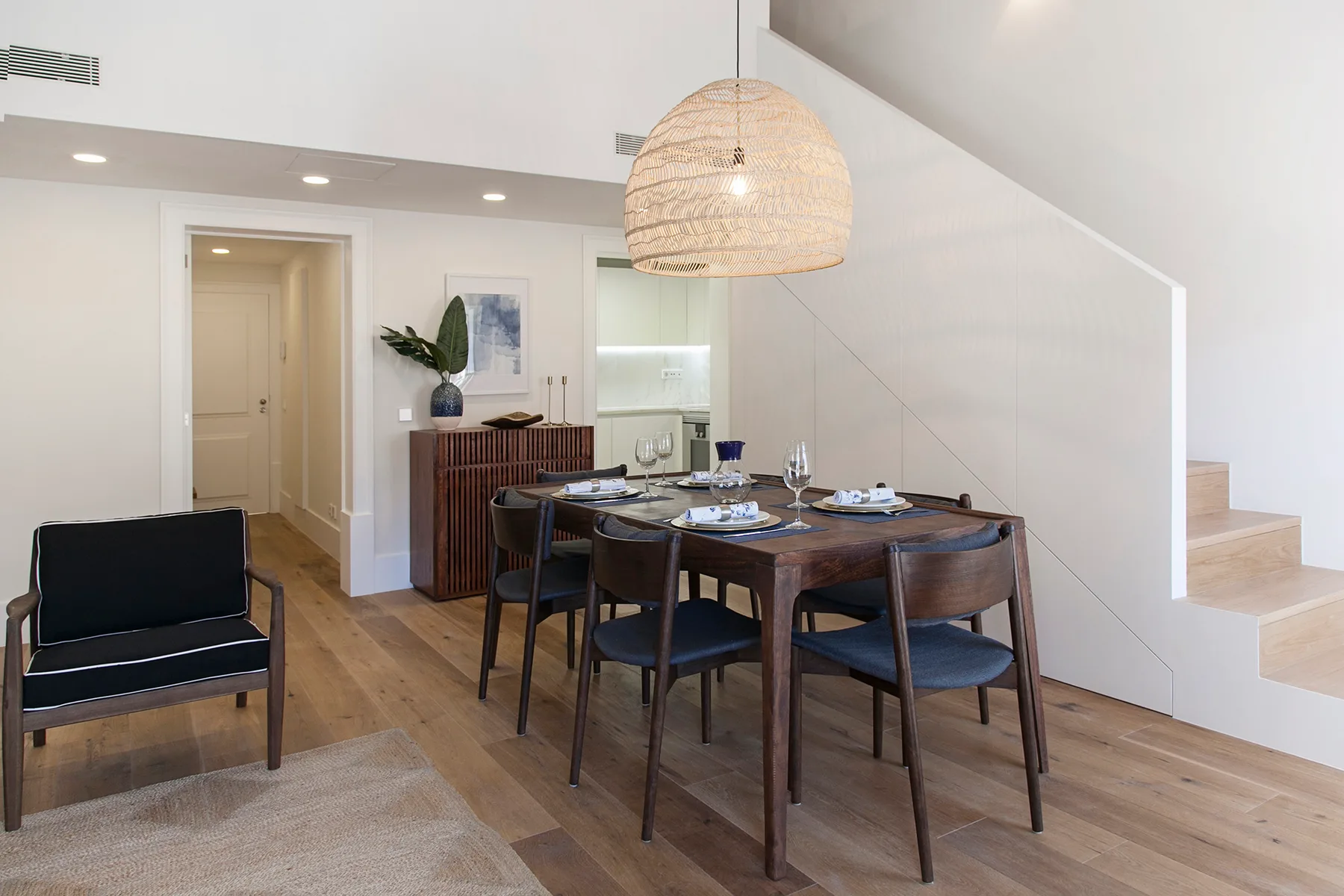 A dining area with a wooden table beneath a woven pendant light.