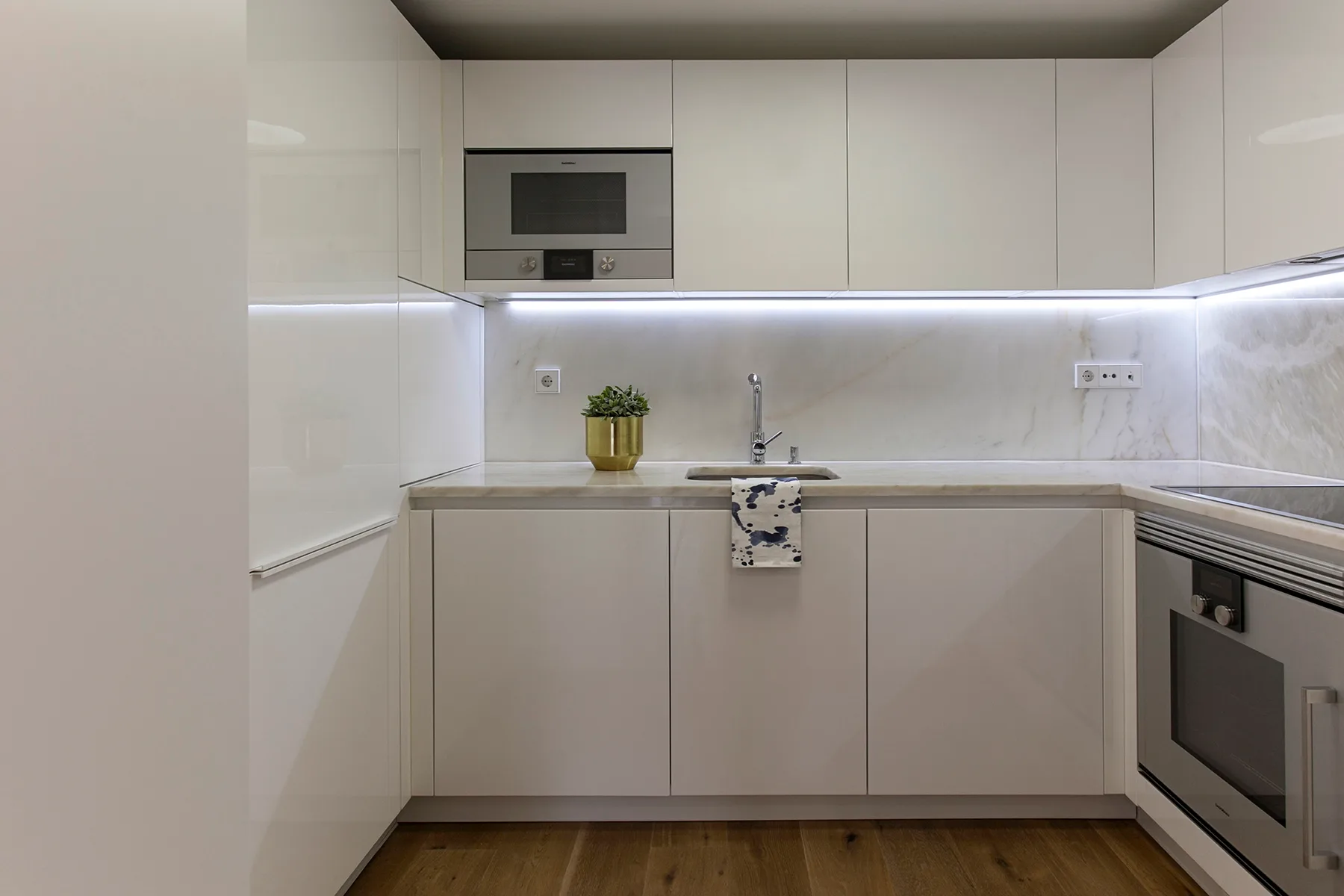 A modern kitchen with white cabinetry, a countertop, and built-in appliances.