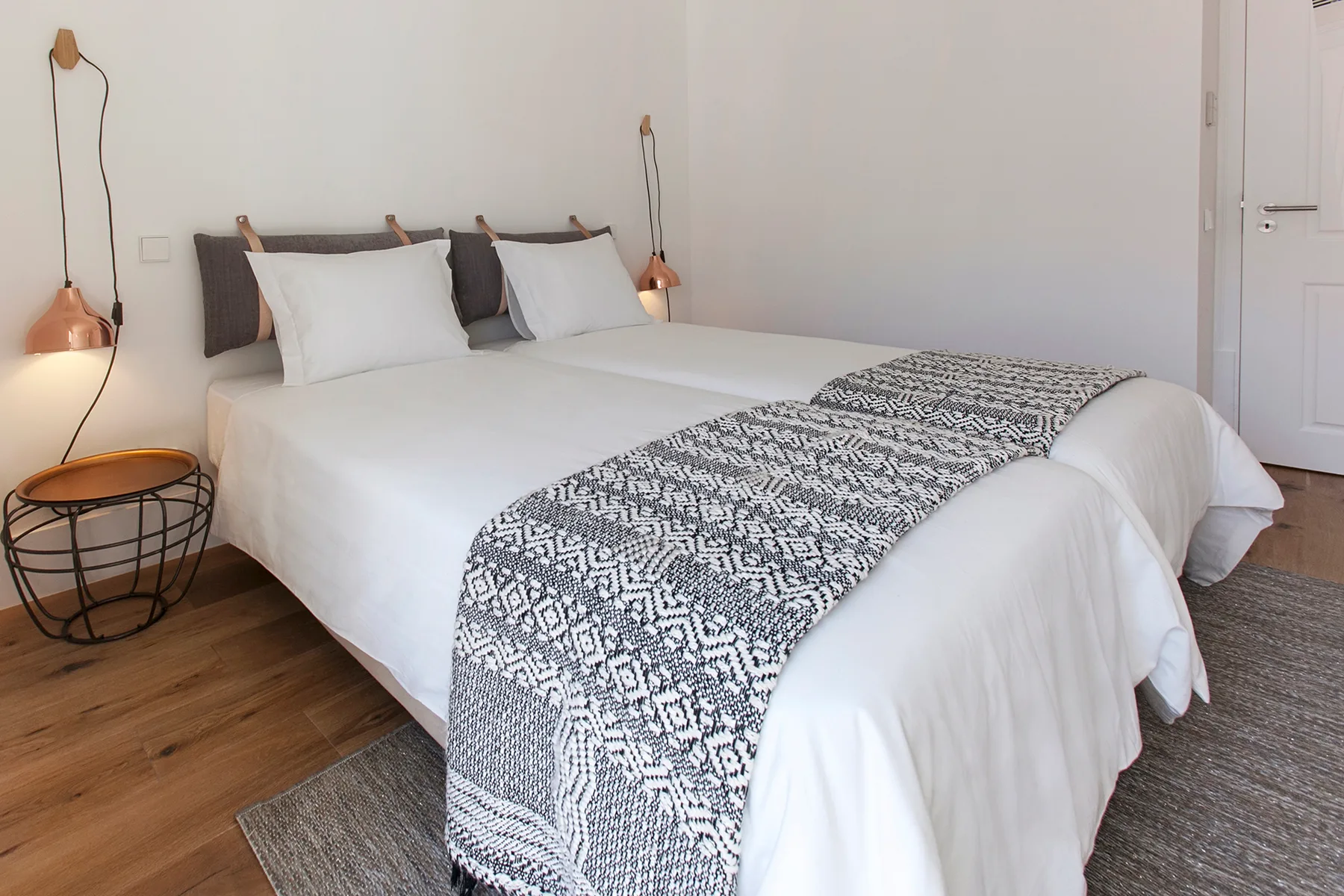 A bright bedroom with a neatly made bed and patterned bed runner.