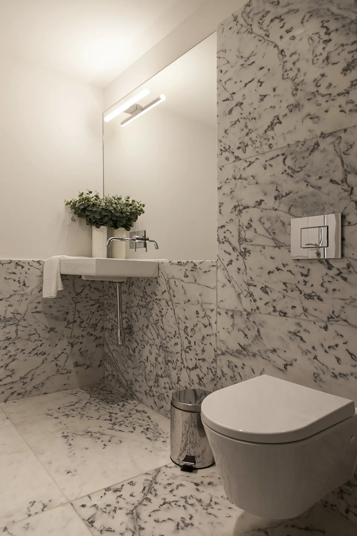 A marble-tiled bathroom with a sink and toilet.