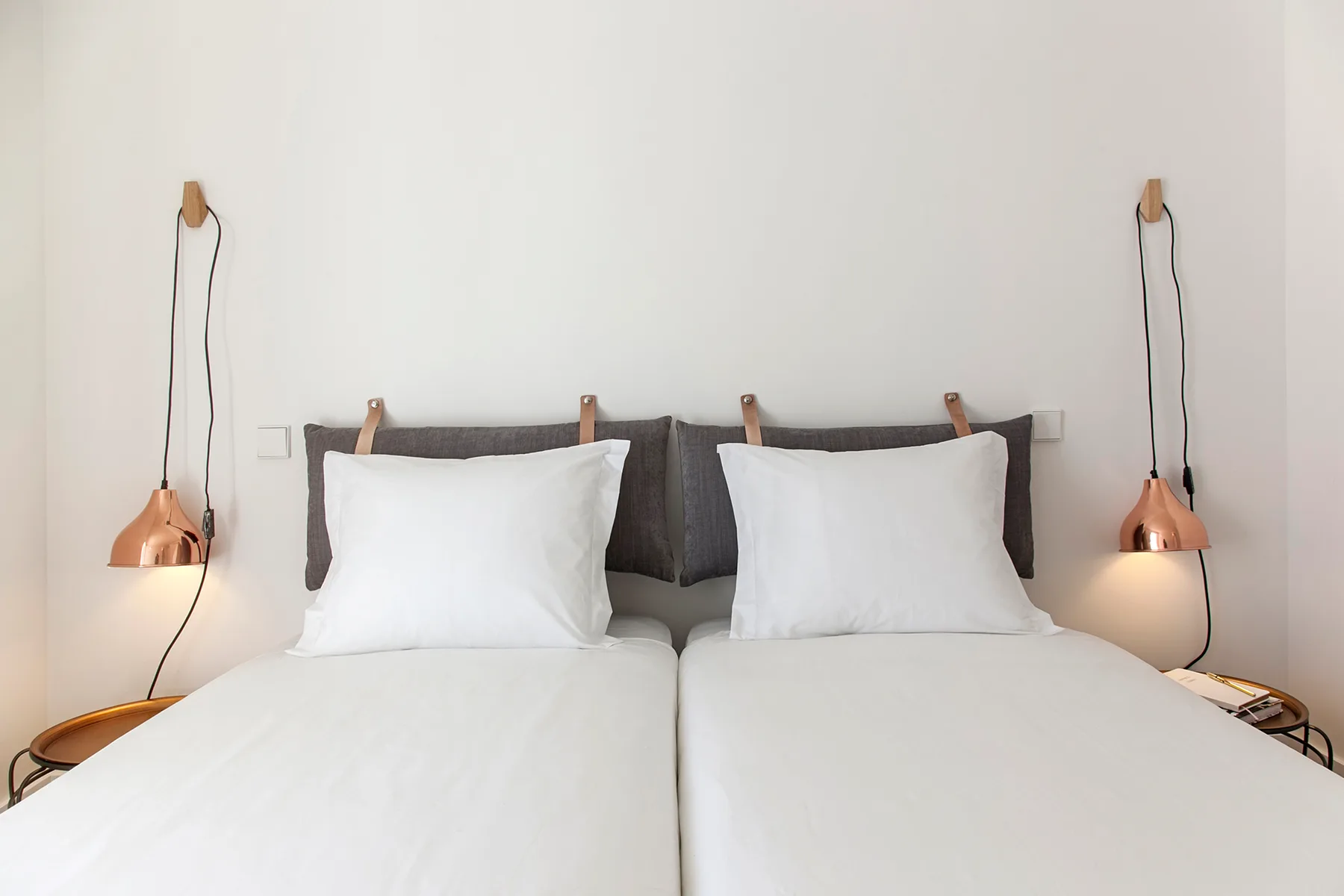 A bedroom with two beds and matching wall-mounted reading lamps.