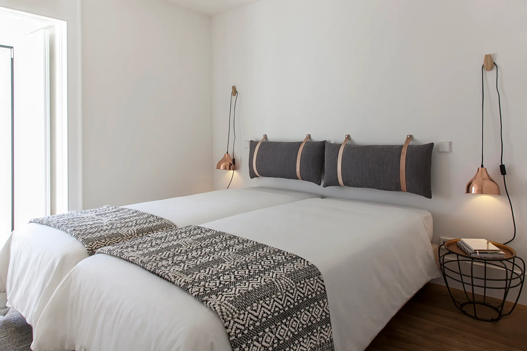 A bedroom with white bedding and a patterned throw across the bed.