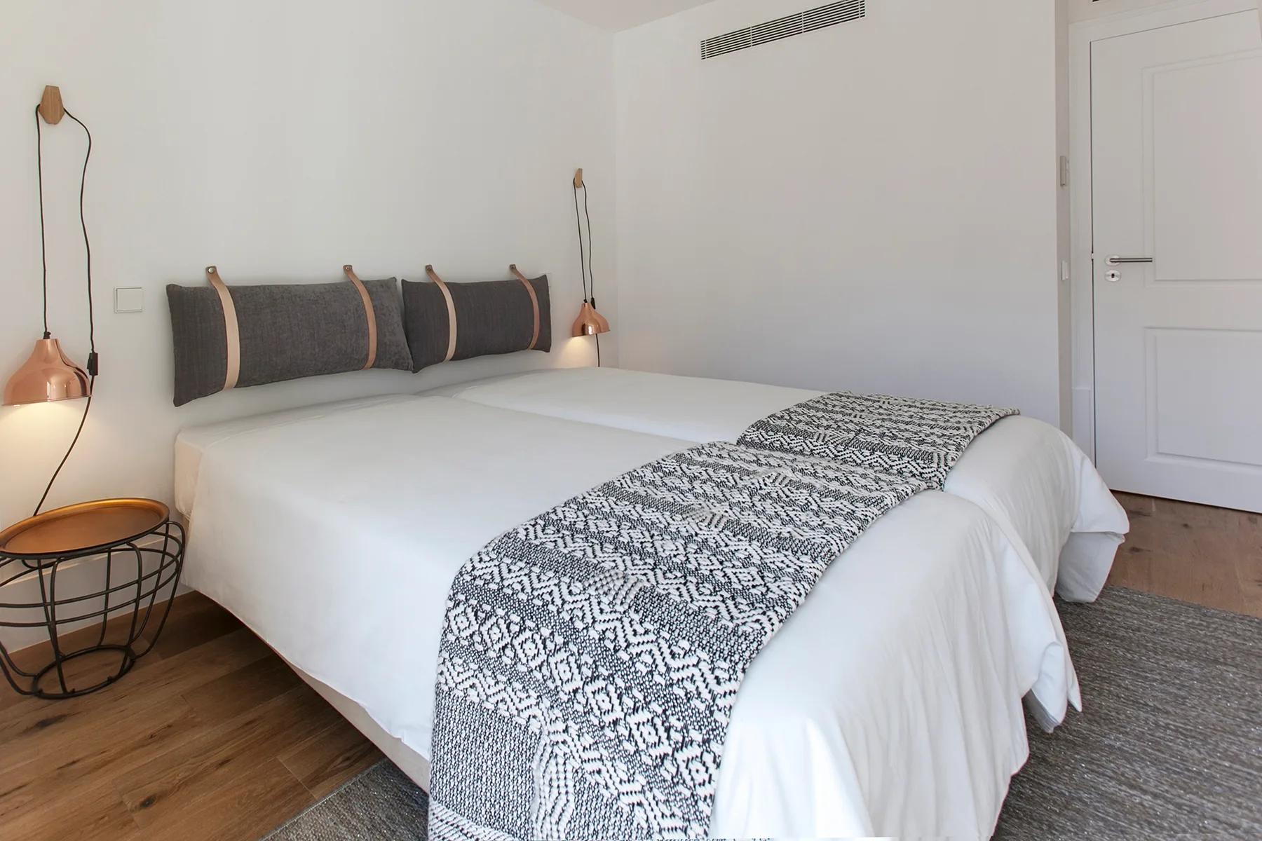 A bedroom with a neatly made bed and patterned runner.