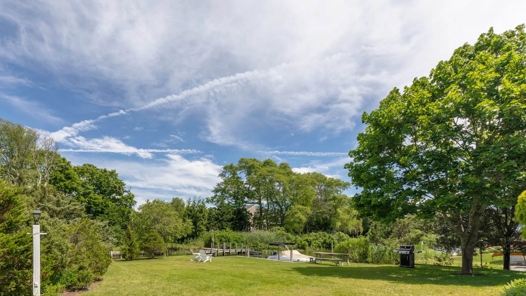 A grassy outdoor area with trees, seating, and a small pond.