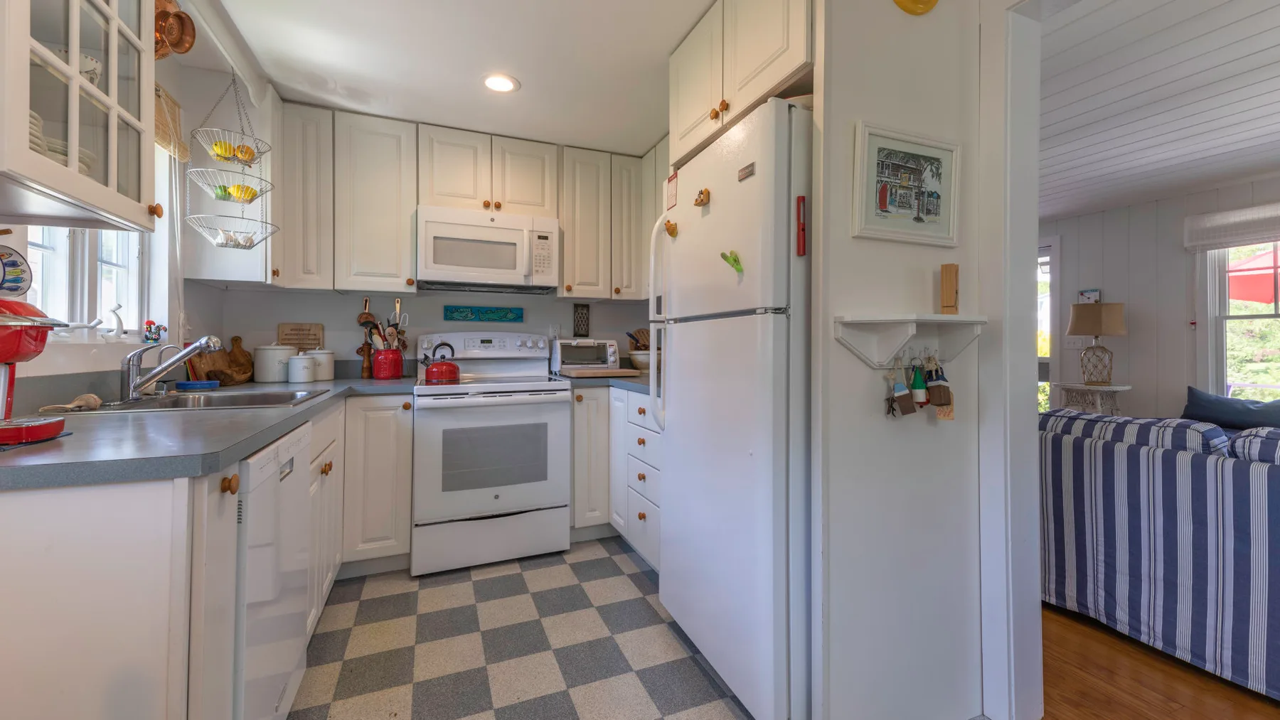 A bright kitchen with white cabinets, appliances, and a checkered floor.