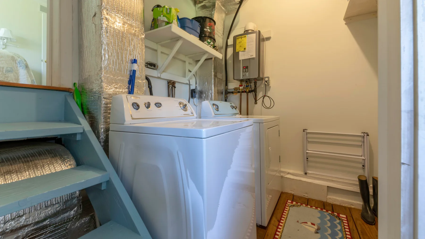 A laundry room with a washer and dryer beneath storage shelves.