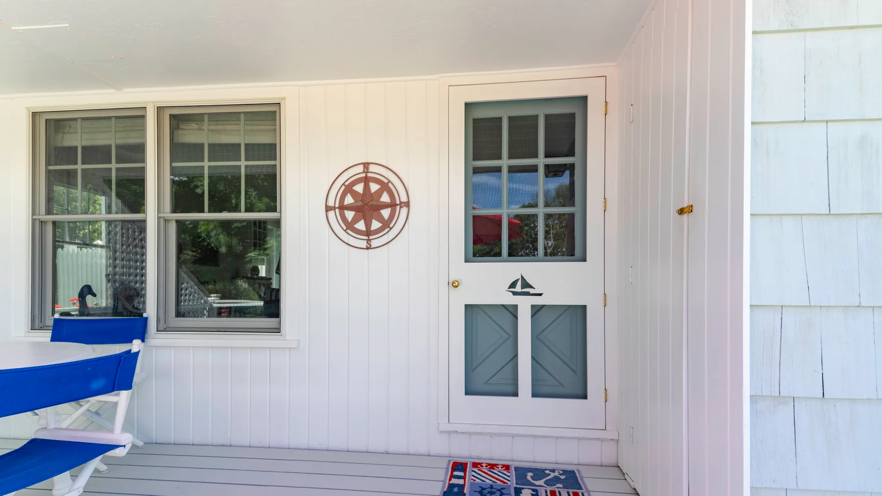 A covered porch with a door, windows, and blue seating.