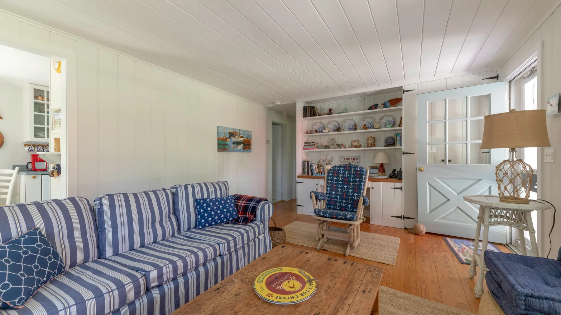 A living room with striped seating, a wooden coffee table, and open display shelves.