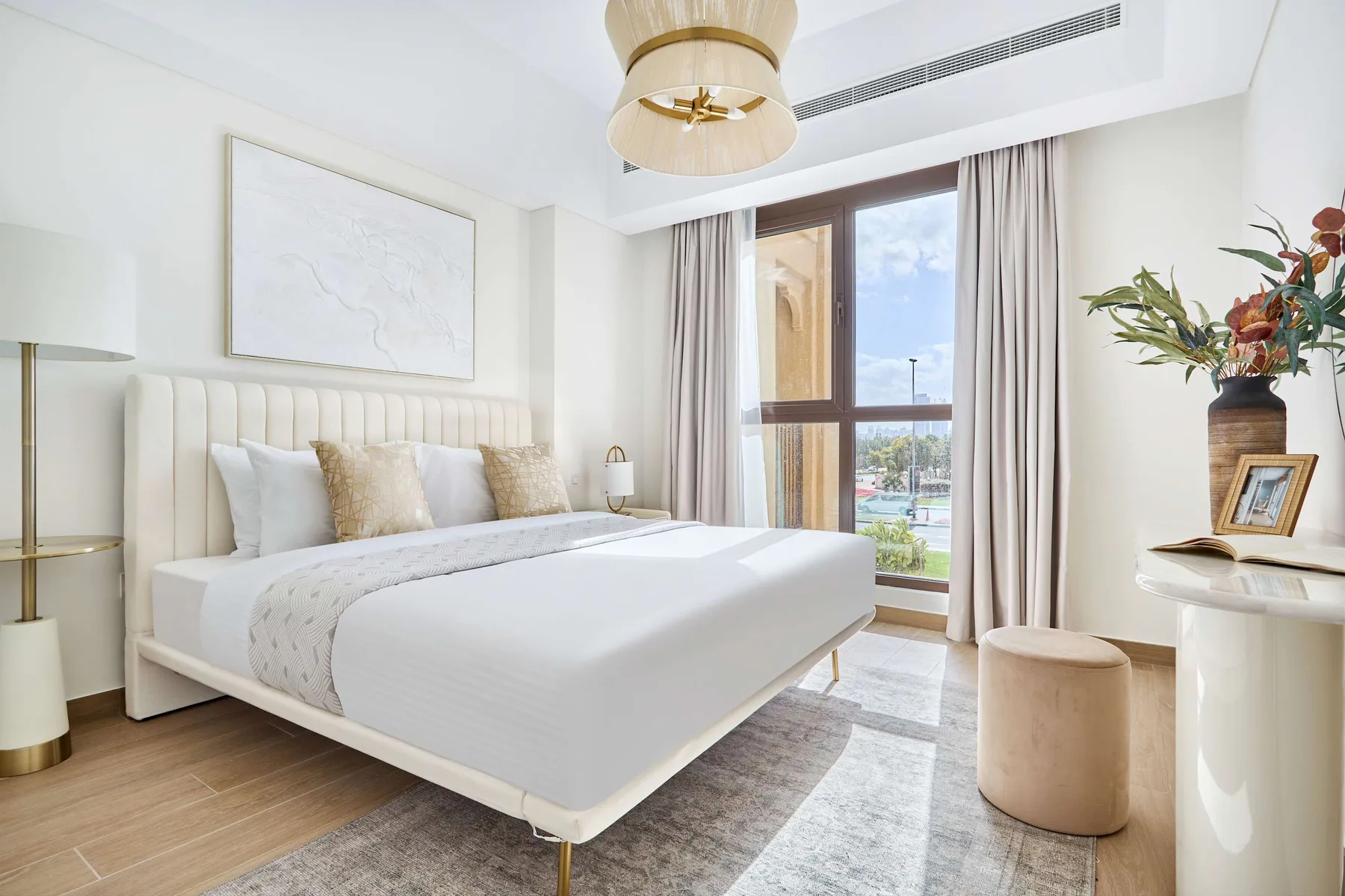 Un dormitorio luminoso con una cama grande junto a una ventana con cortinas.
