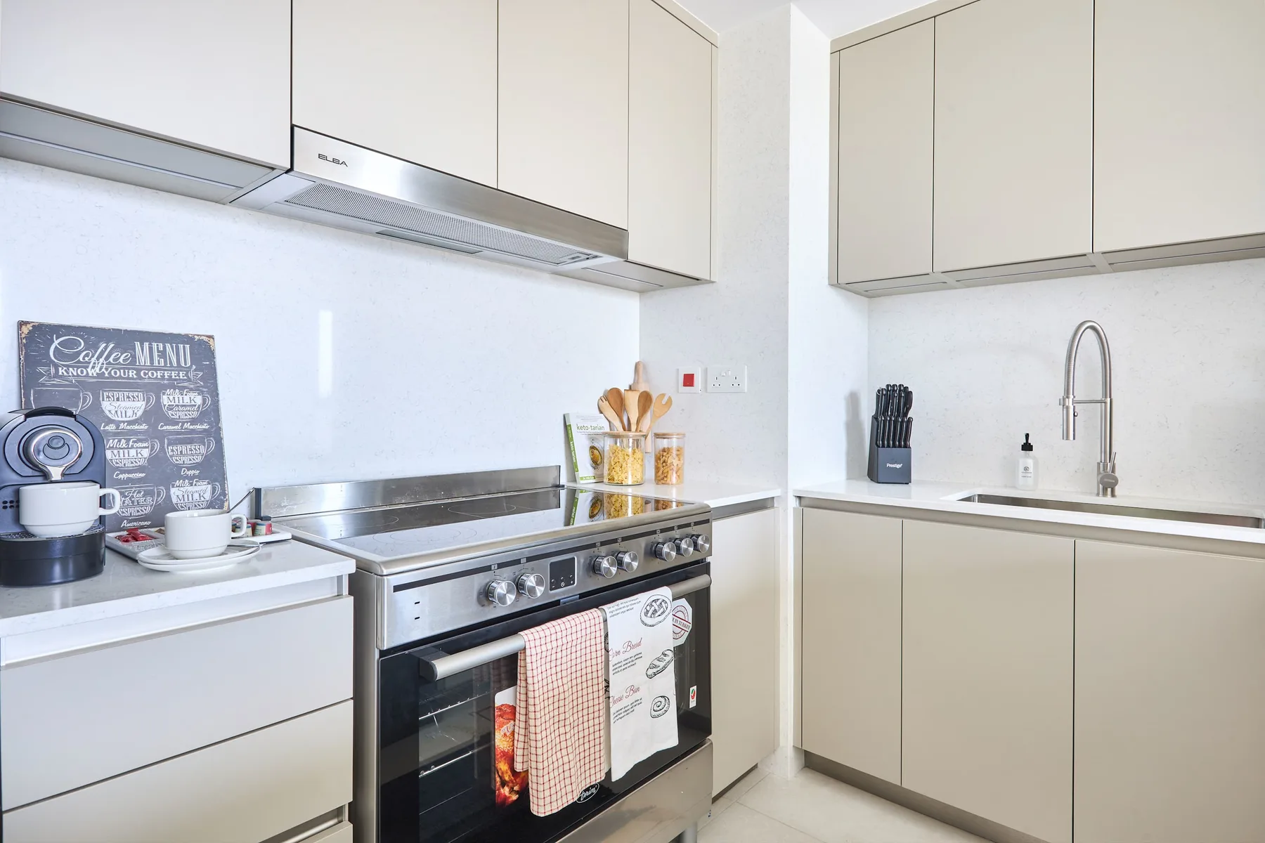 Una cocina luminosa con estufa de encimera, fregadero y armarios claros.