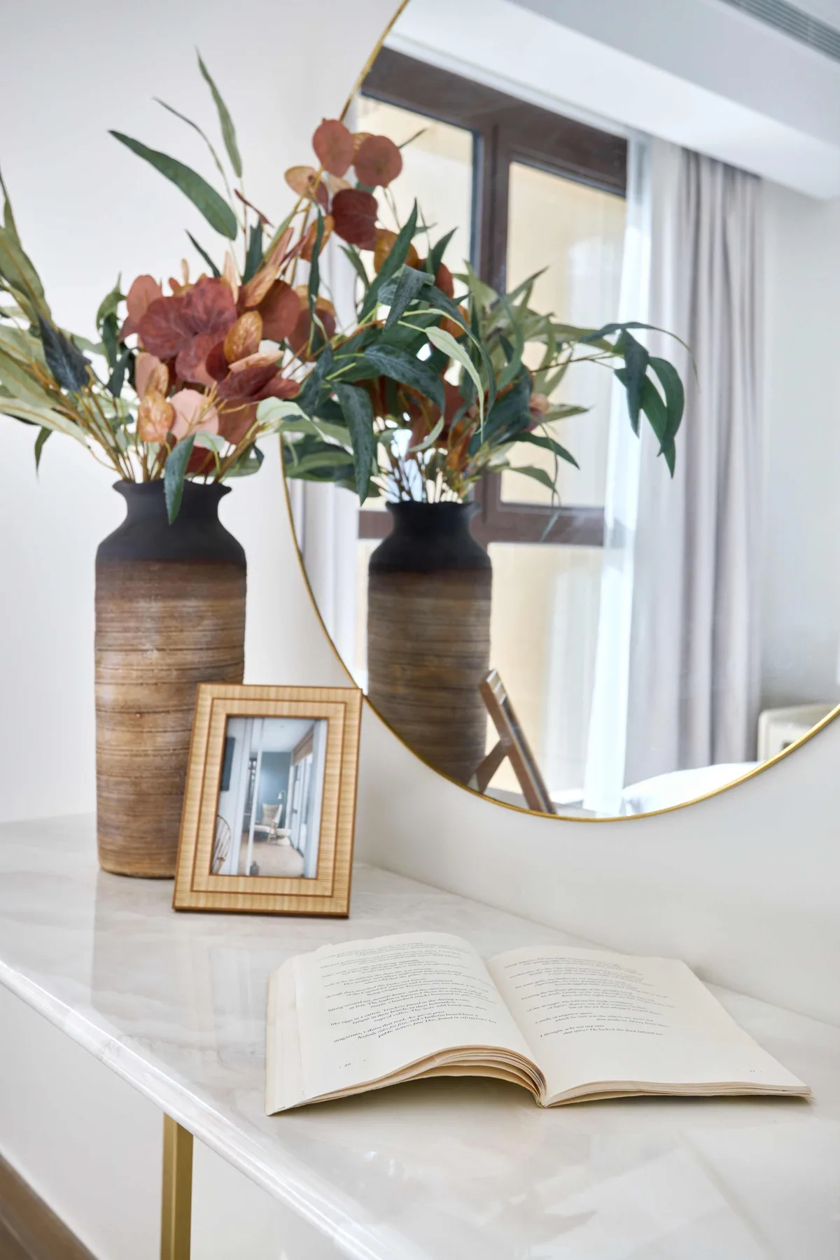Una habitación luminosa con un libro abierto y arreglos florales sobre una mesa blanca.