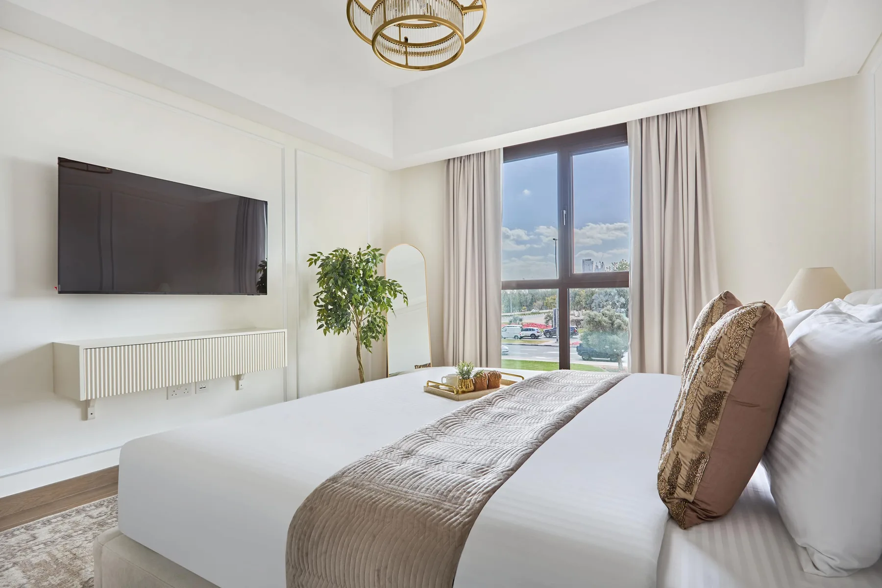 Un dormitorio luminoso con una cama grande junto a una ventana alta.