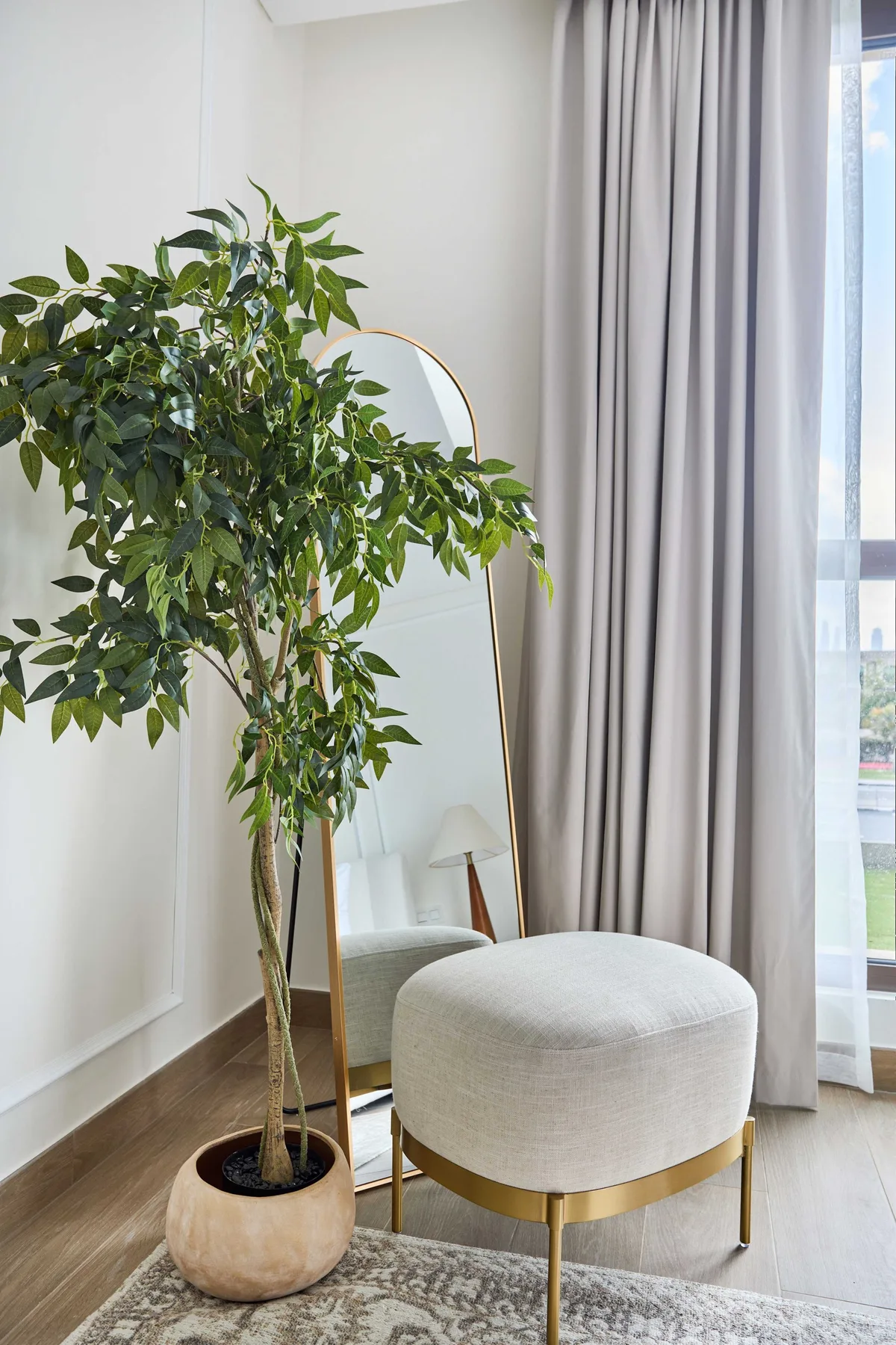 Una luminosa zona de estar con un árbol frondoso en maceta junto a una silla tapizada.