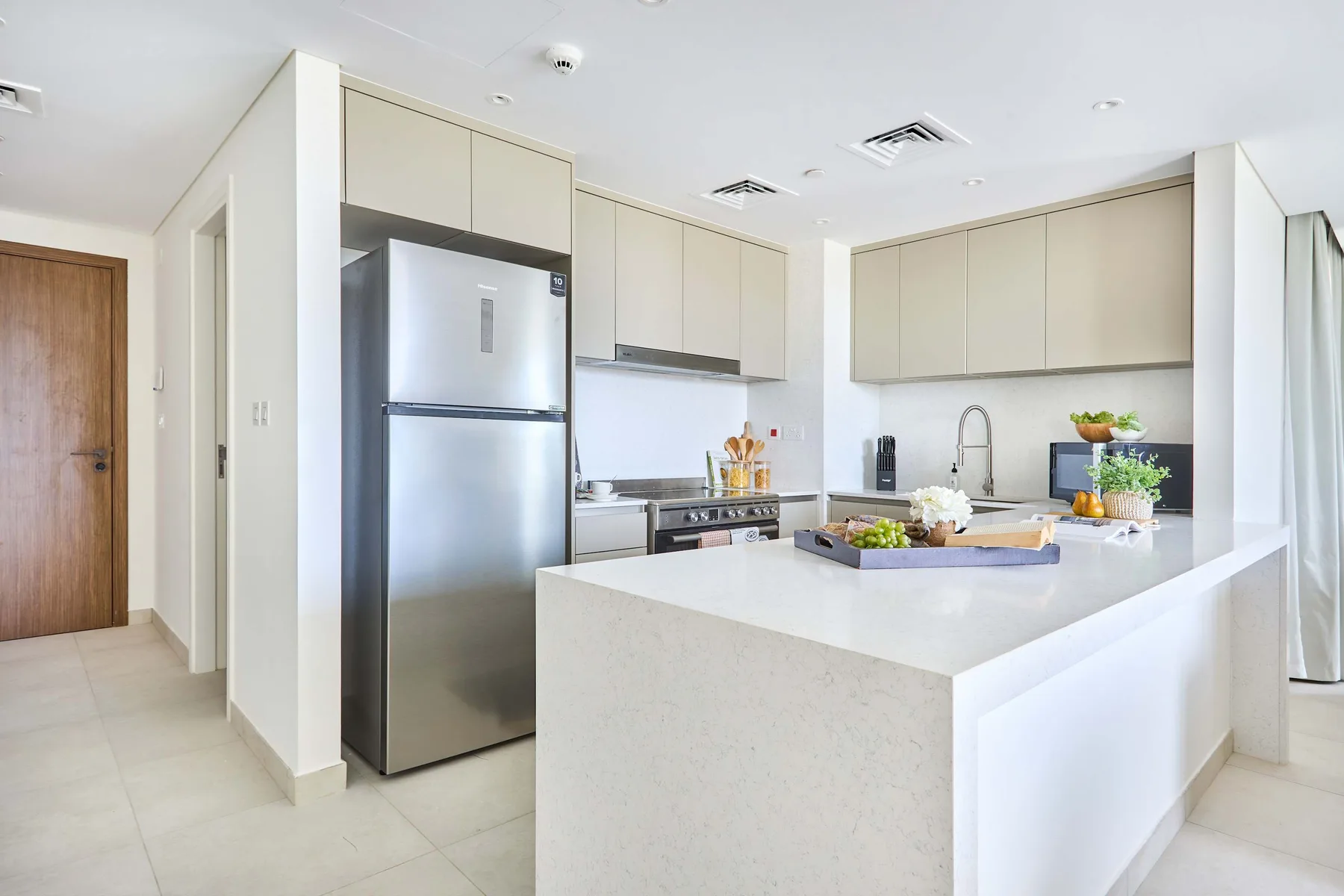 Una cocina moderna y luminosa con gabinetes claros y una isla grande.