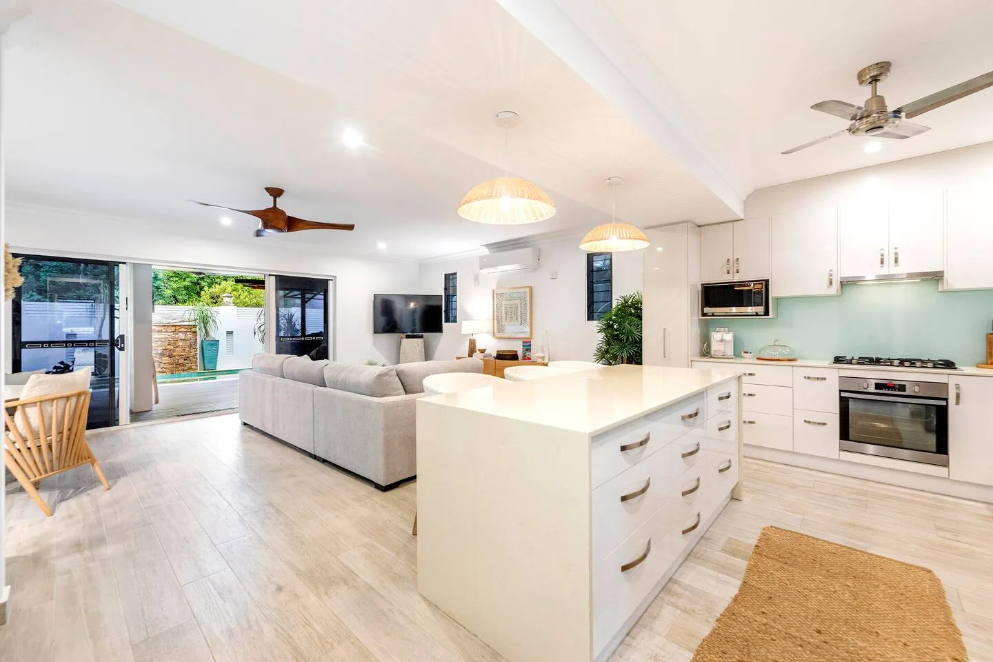 An open-plan living room and kitchen with sliding glass doors opening to an outdoor patio.
