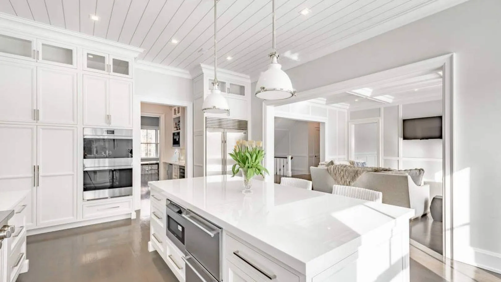 Una cocina luminosa con una gran isla blanca y una sala de estar contigua.