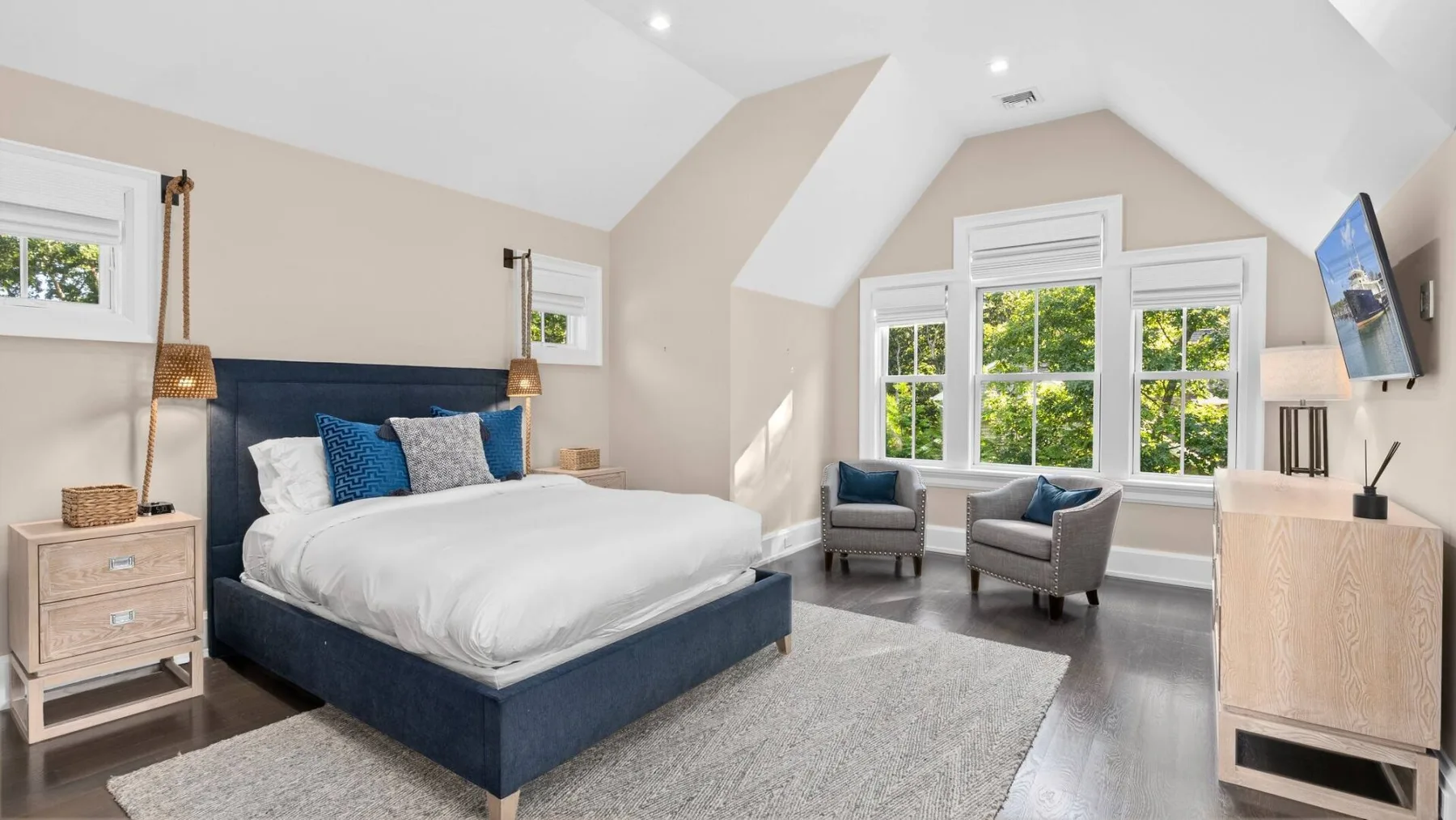 Un dormitorio luminoso con una cama y una zona de asientos junto a grandes ventanas.