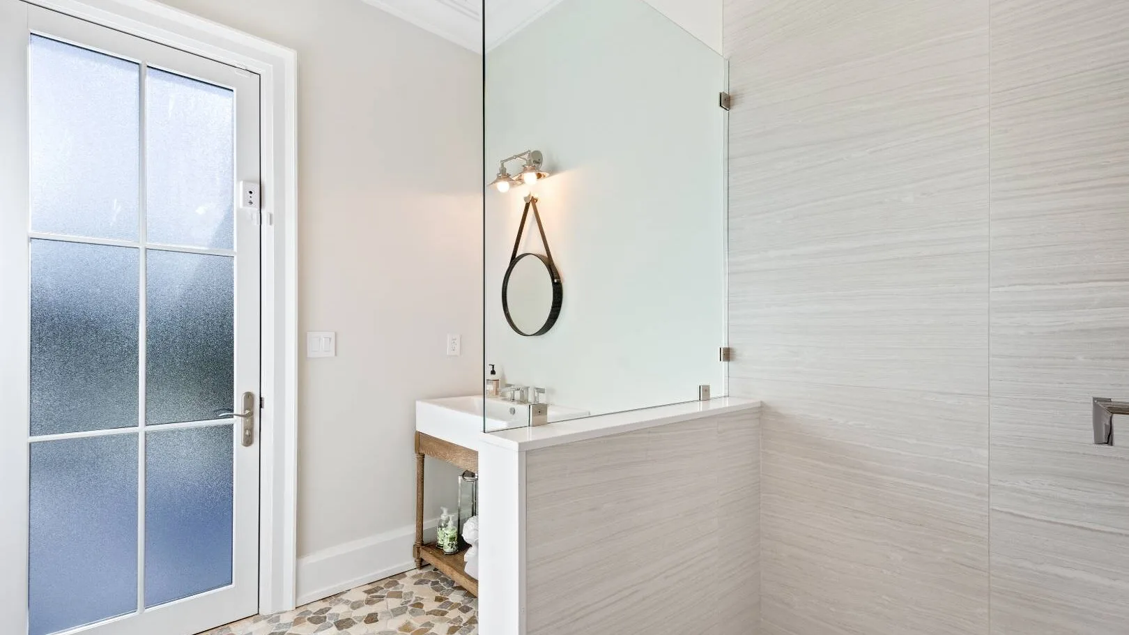 Un lavabo de baño está junto a una zona de ducha de vidrio.