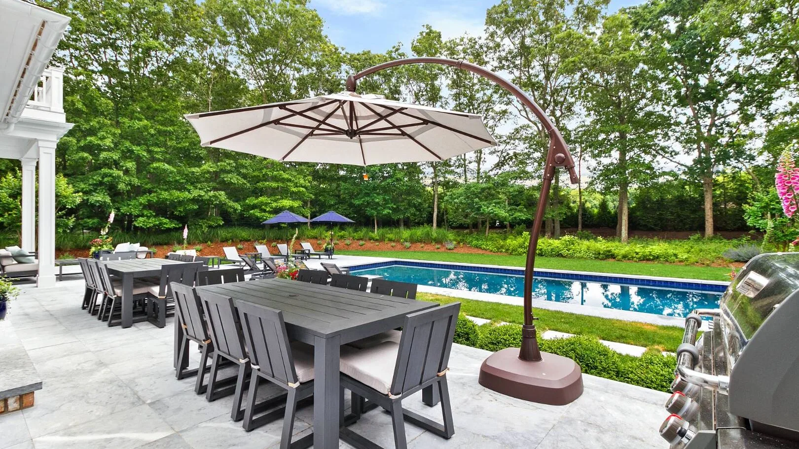 Un patio exterior tiene mesas y asientos junto a una piscina.