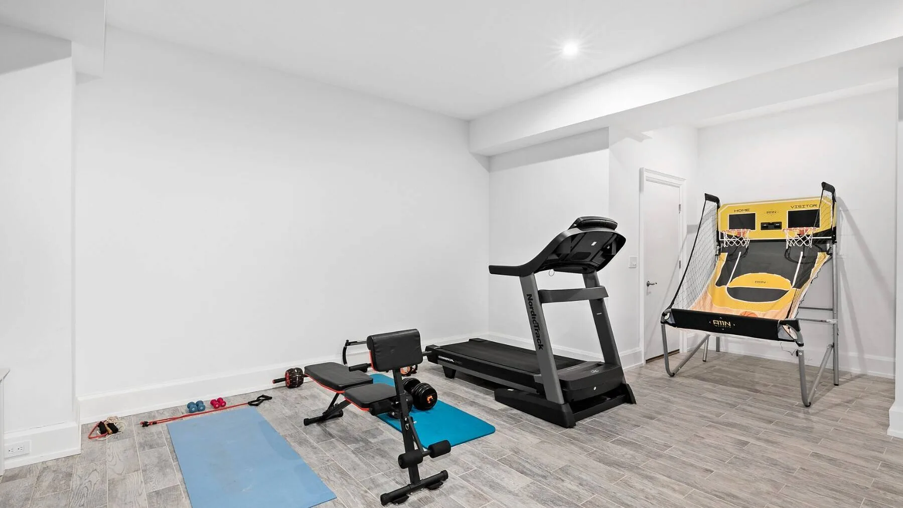 Un gimnasio en casa con una cinta de correr, un banco de ejercicios y equipo de entrenamiento.