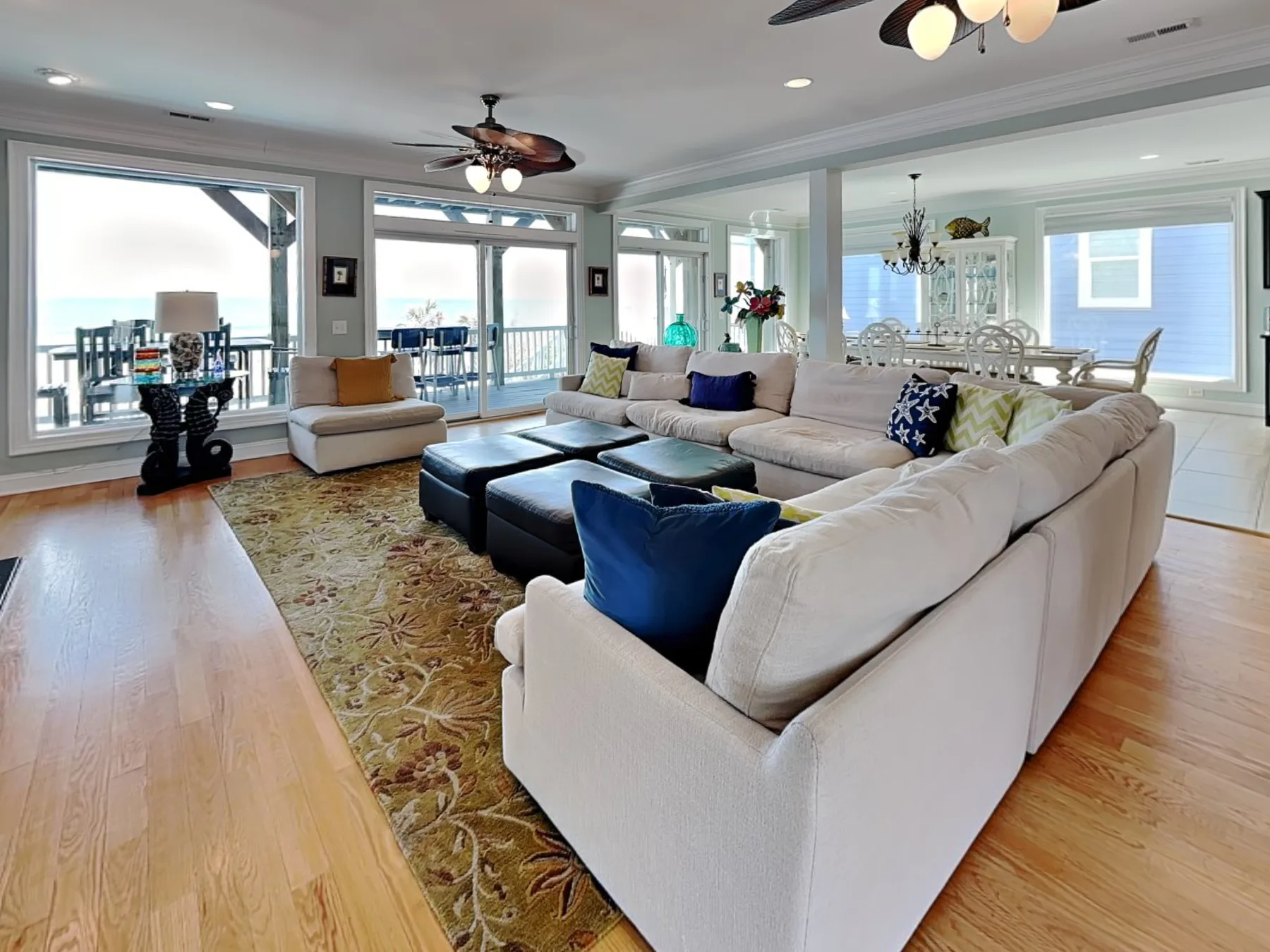 A bright living room with sectional seating, a patterned rug, and large windows.
