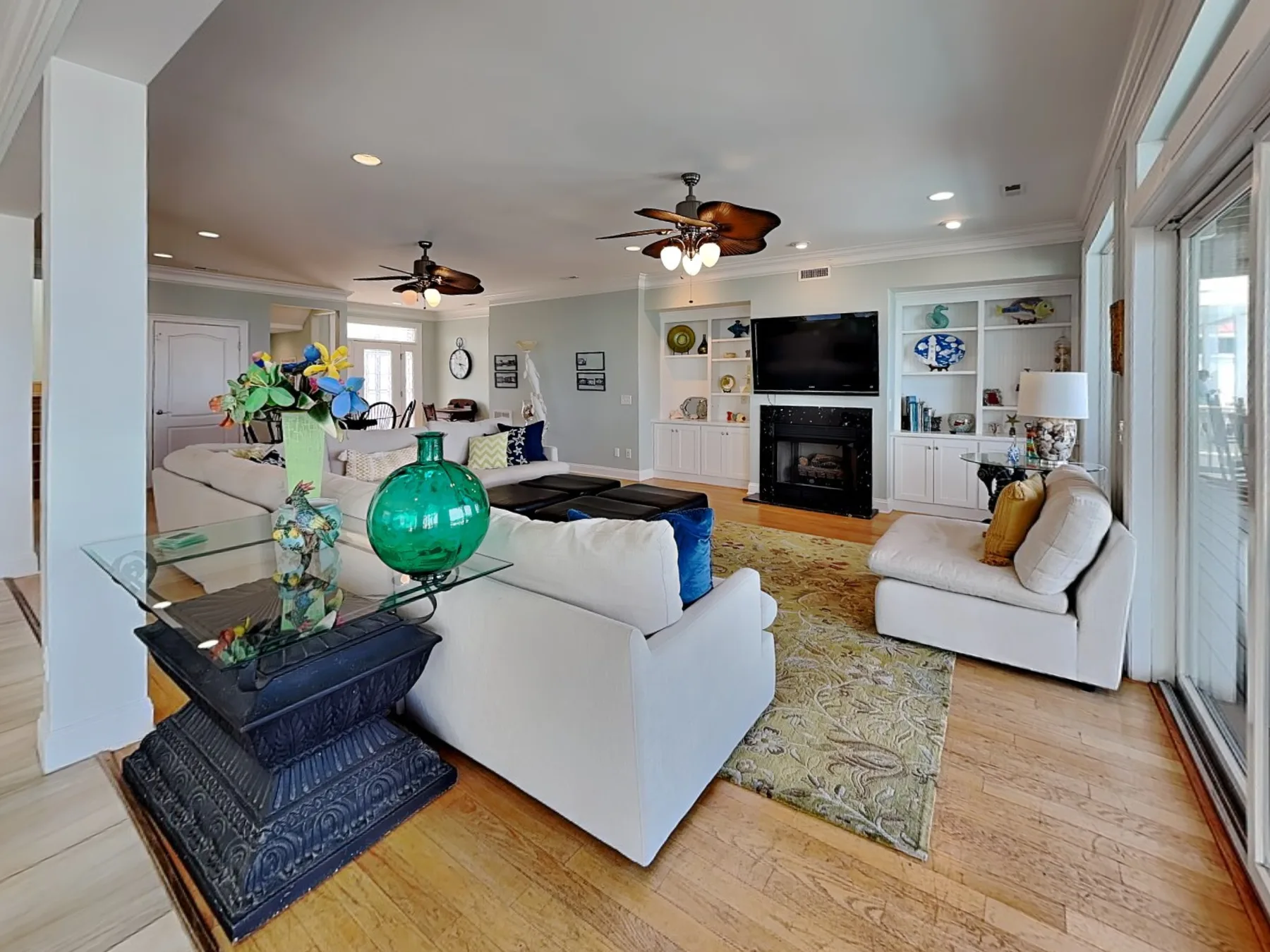 A spacious living room with white seating, a fireplace, and a television.