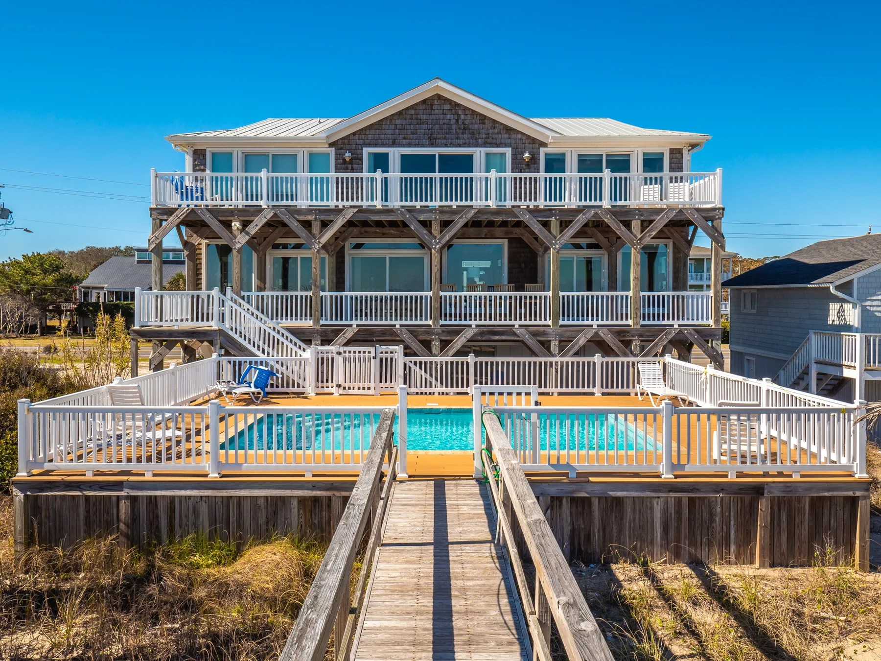 A large beachfront-style house with wooden decks and a swimming pool.