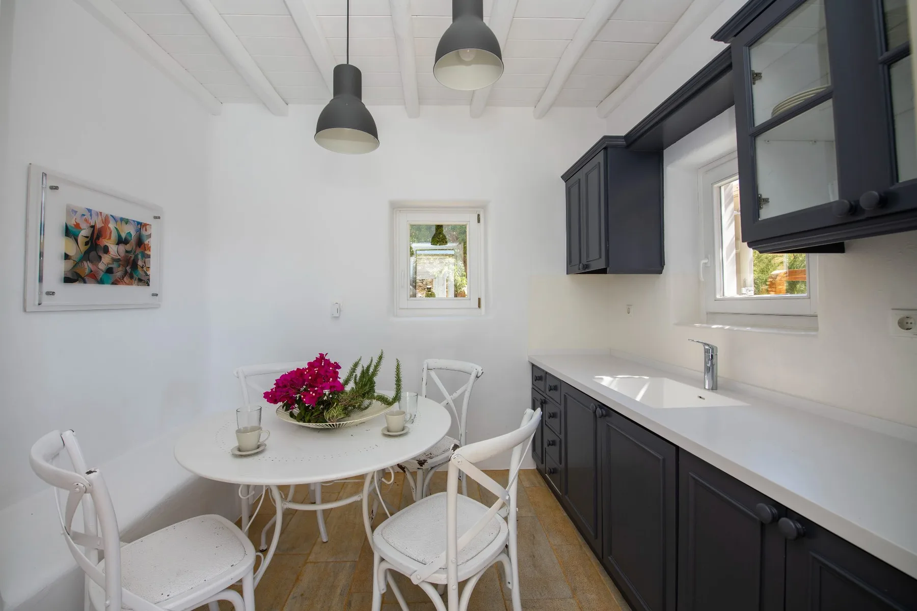 Una luminosa cocina con comedor, una mesa pequeña y armarios oscuros.
