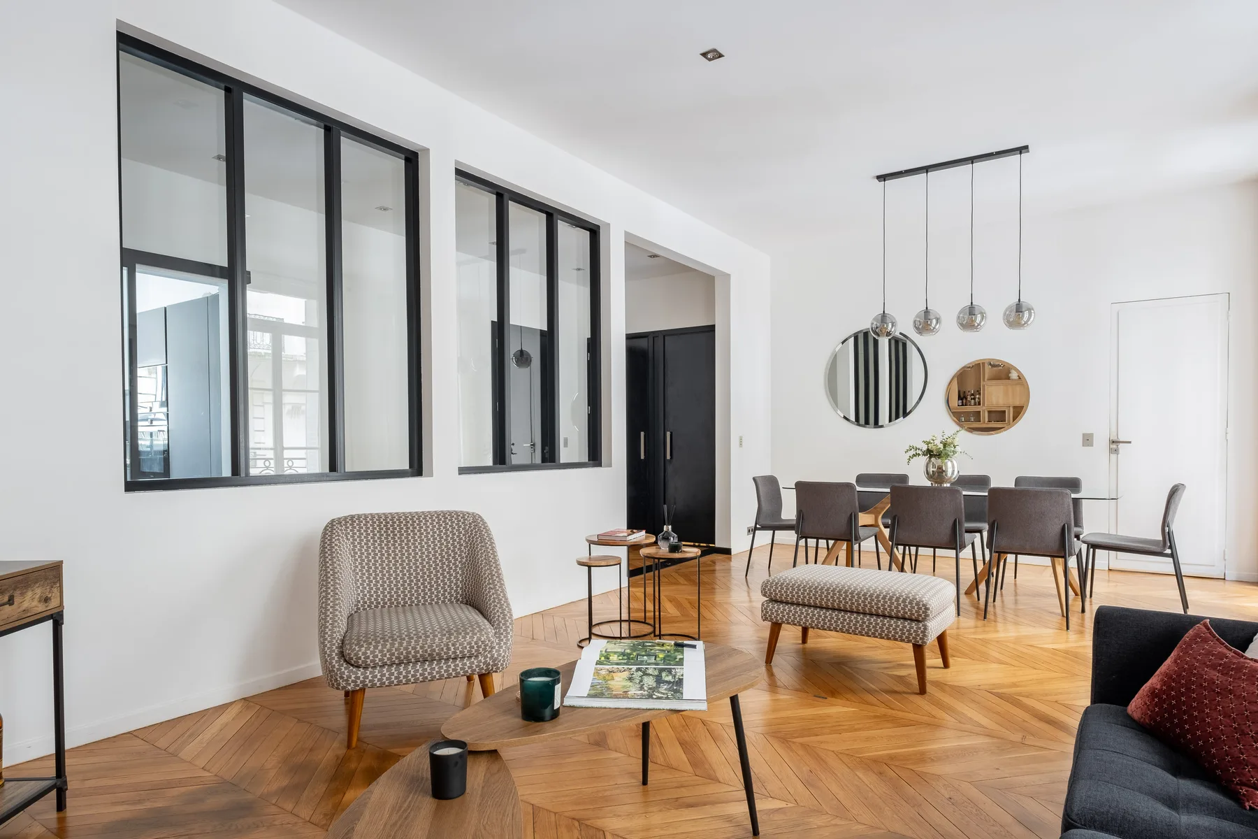 Una luminosa sala de estar y comedor con asientos, una mesa y ventanas interiores altas.