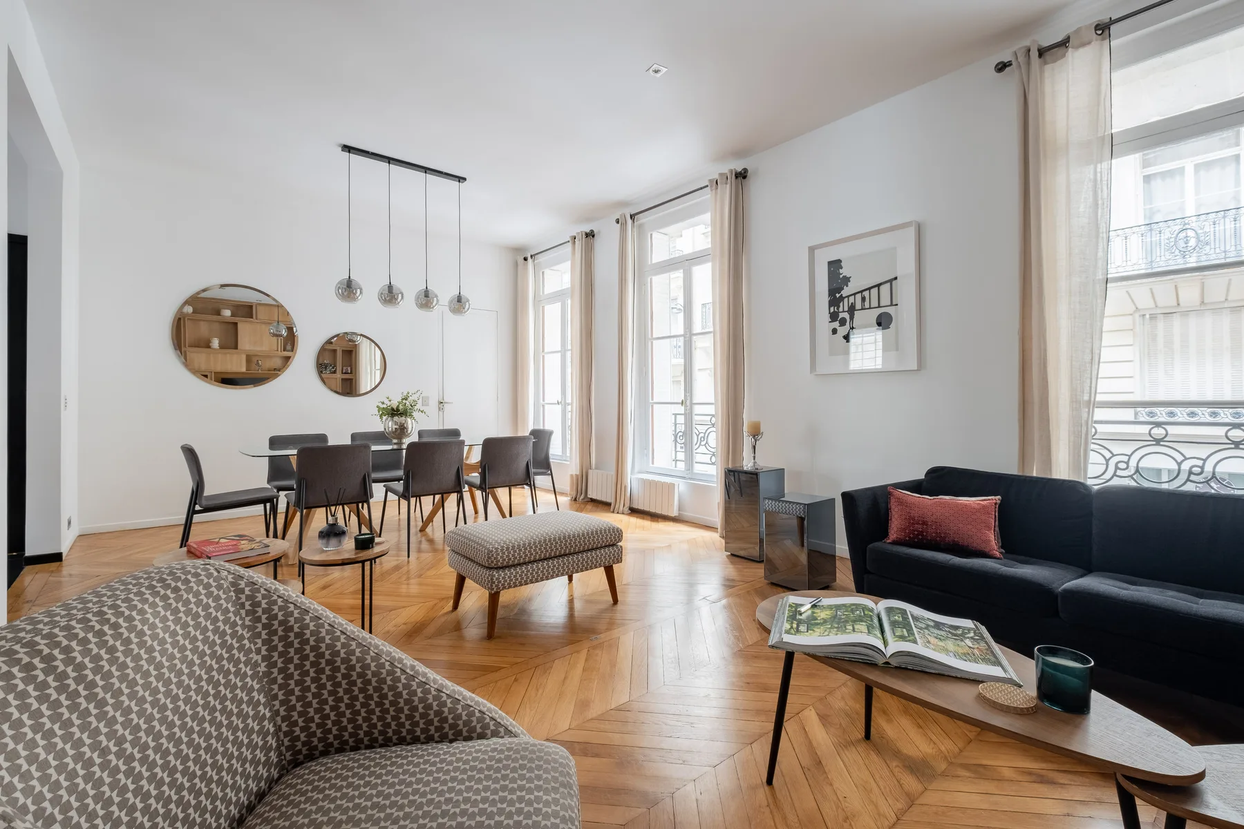 Una luminosa sala de estar y comedor con asientos, una mesa y ventanas altas.