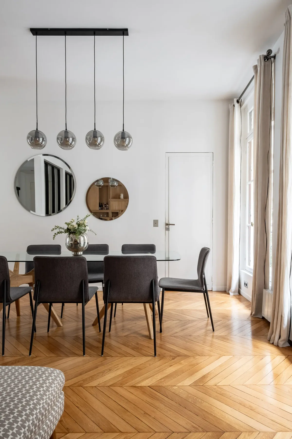 Comedor con mesa de vidrio, asientos oscuros y lámparas colgantes.