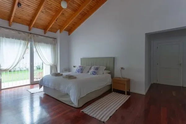 A bedroom with a bed beside large windows and a striped rug.