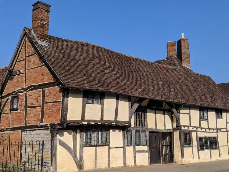 A historic half-timbered house with a steep tiled roof under a clear blue sky.