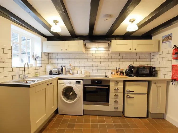 A kitchen with cream cabinets, tiled walls, and a washing machine.