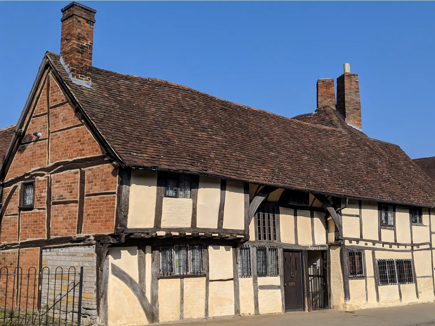 A historic timber framed building with leaded windows and a tiled roof at One Masons Court in Stratford upon Avon