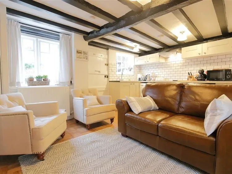 A living room with a brown sofa and light-colored armchairs.