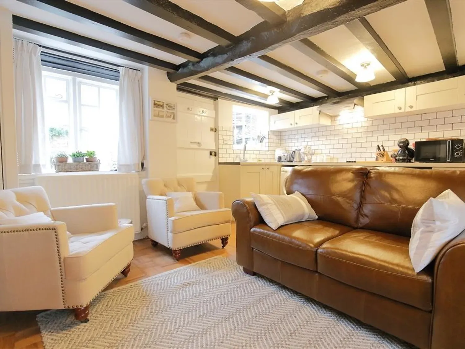A living room with seating in the foreground and a kitchen in the background.