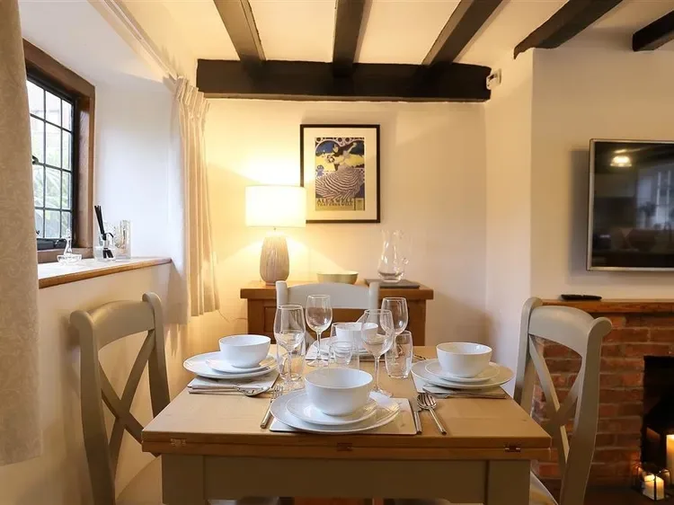 A dining area with a wooden table set with dishes and glassware.
