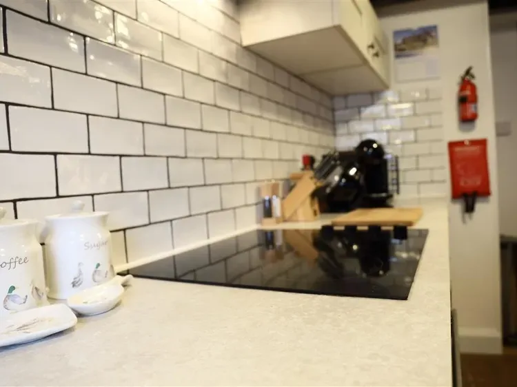 A kitchen counter with a coffee machine, utensils, and a black cooktop.