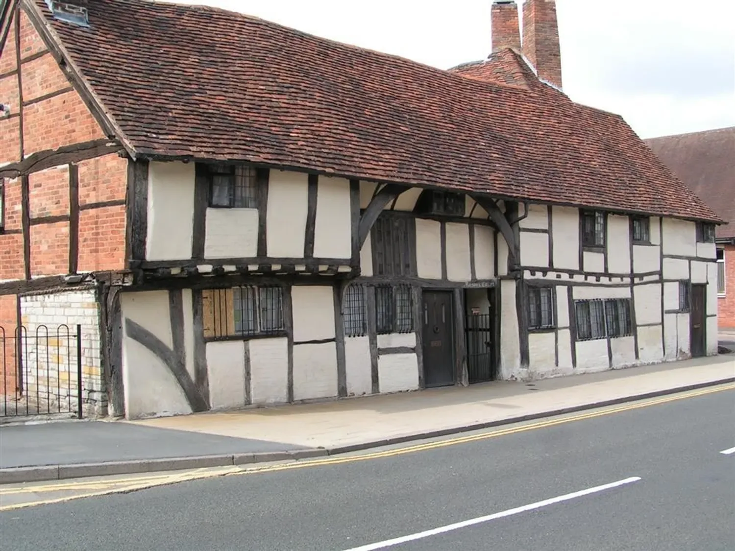 A historic timber framed building with white walls and dark wood beams on a street corner at One Masons Court in Stratford upon Avon