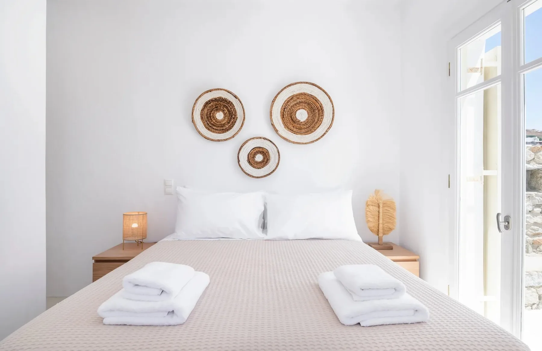 Un dormitorio luminoso con una cama bien hecha y adornos tejidos en la pared.