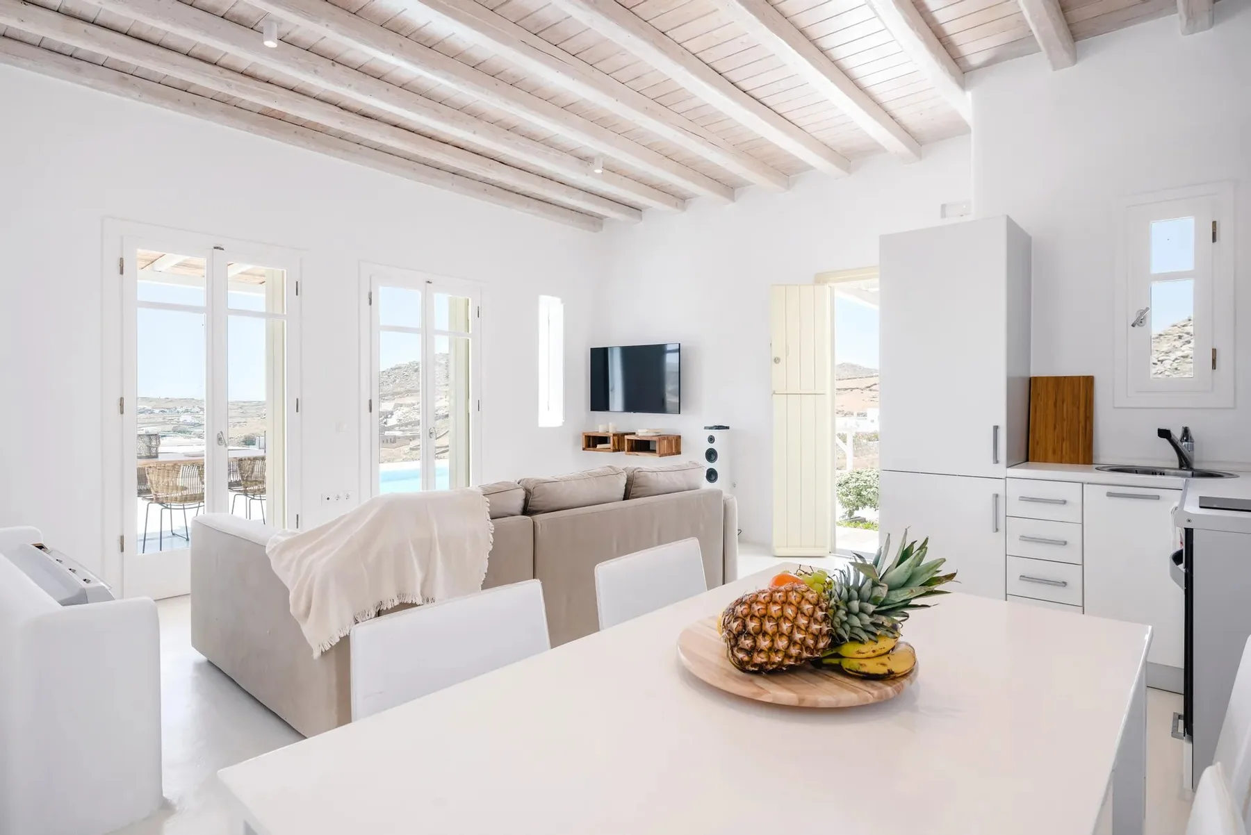 A bright open-plan living area and kitchen with a fruit bowl on the counter.