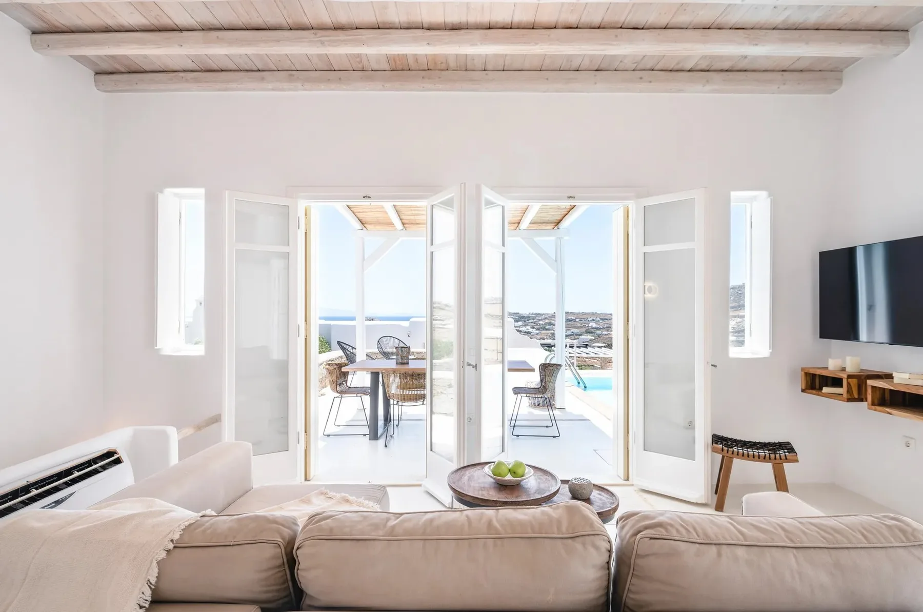 A bright living room opens onto a terrace with seating and a sea view.