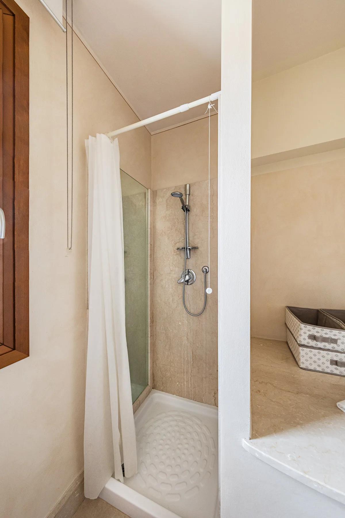 A shower with a white curtain and a handheld showerhead.