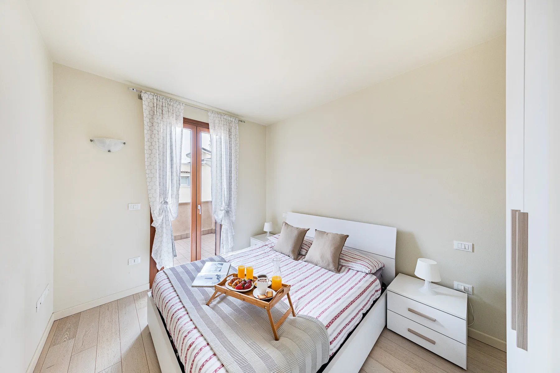 A bright bedroom with a bed and a small table holding breakfast.