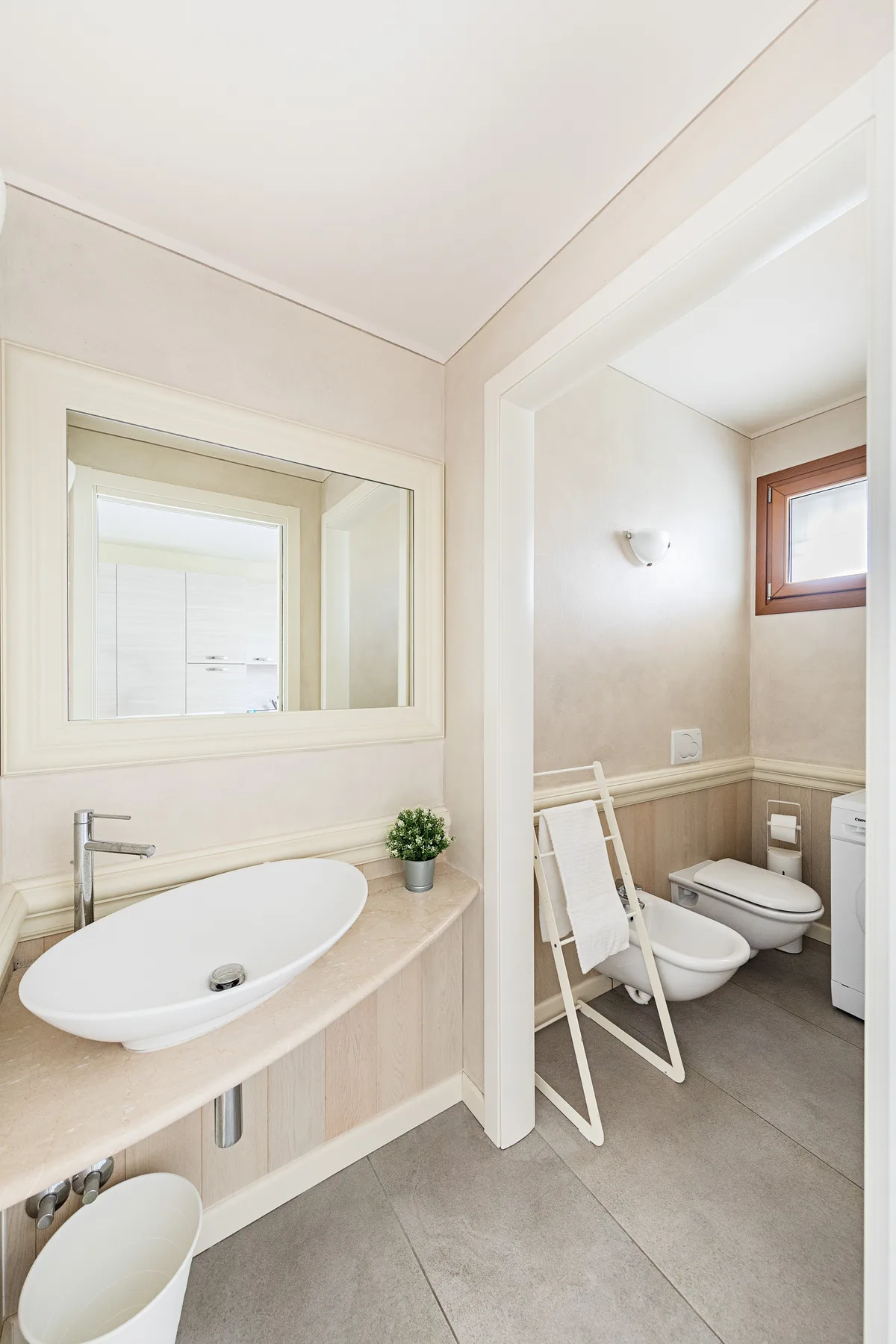 A bathroom with a sink, mirror, and a toilet in an adjoining area.