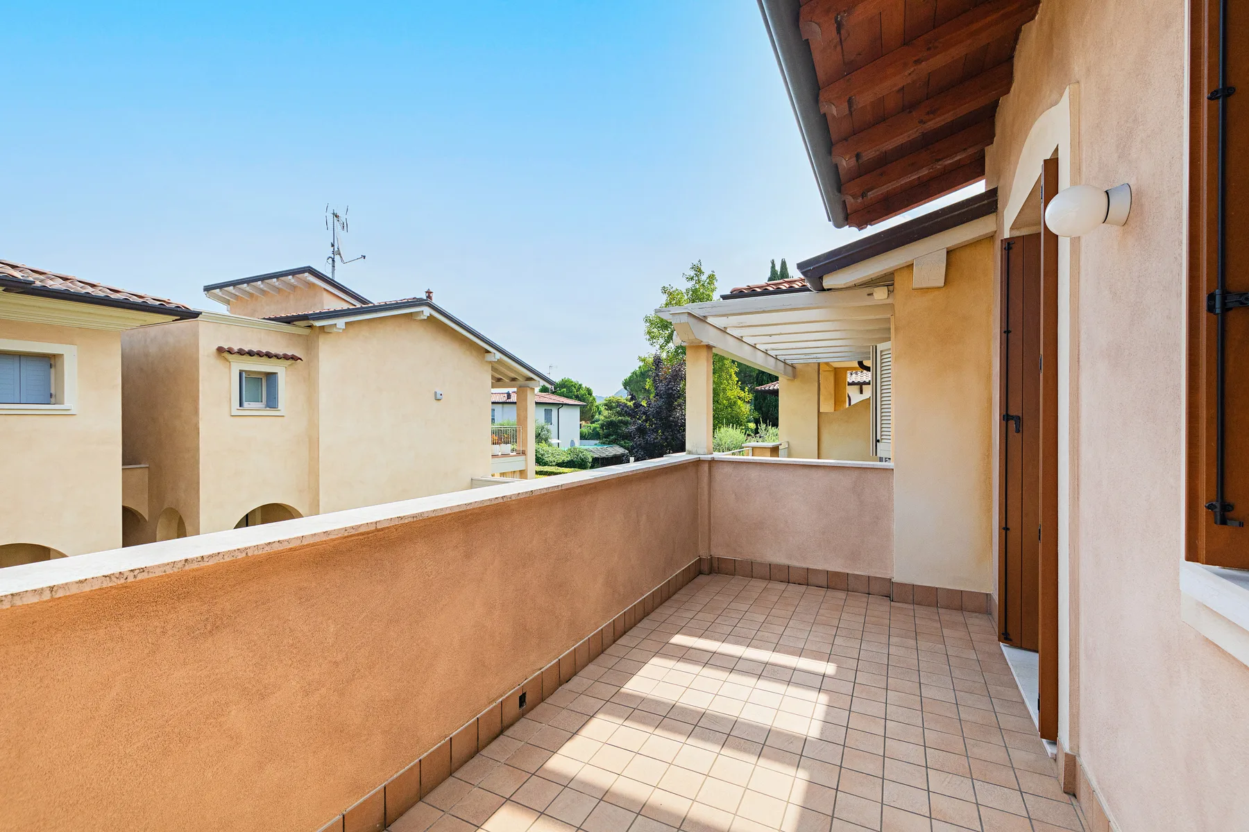 A tiled terrace overlooks neighboring buildings beneath a clear blue sky.