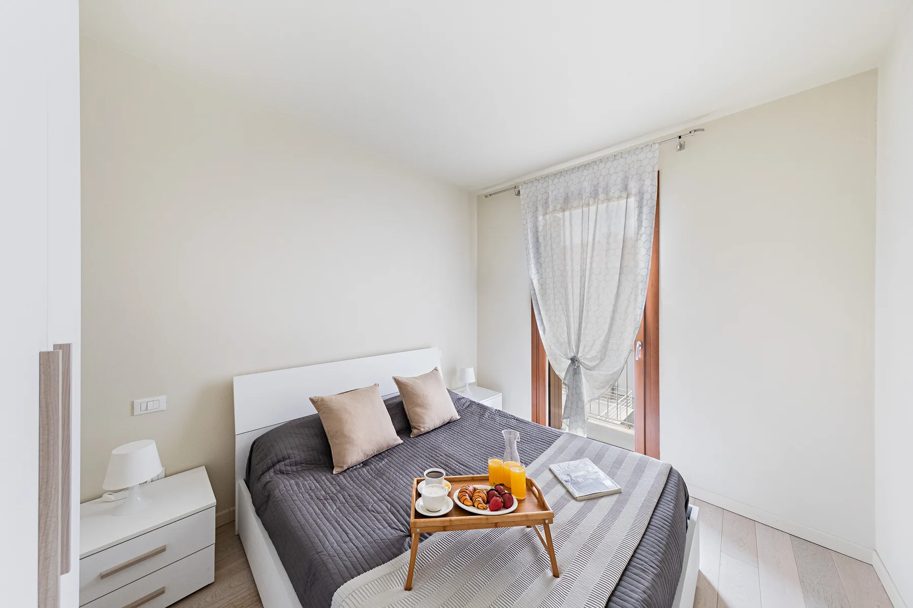 A bright bedroom with a bed and a small breakfast tray.